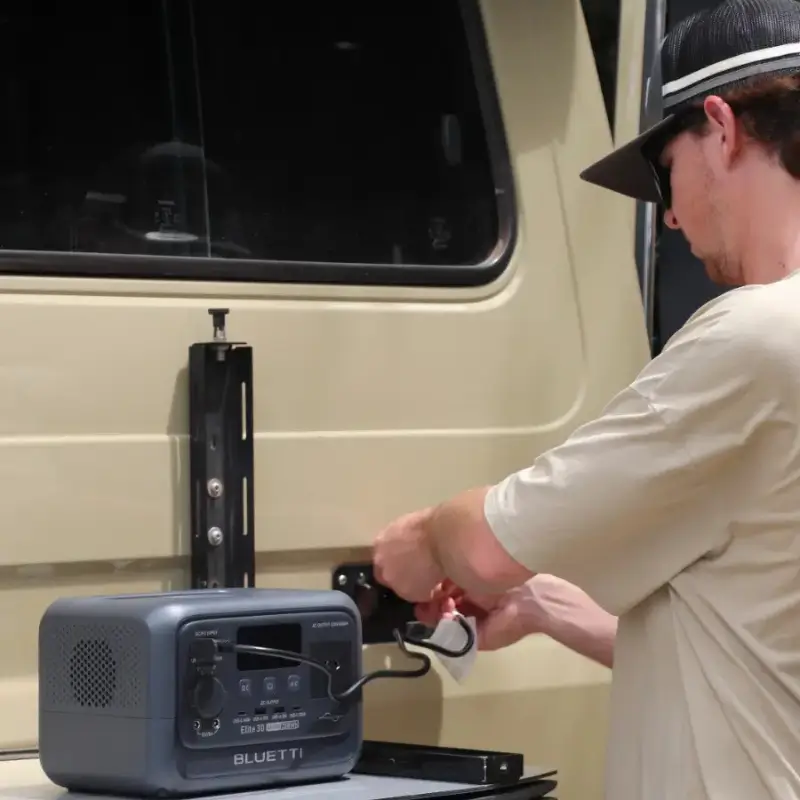 Review Bluetti Elite 30 v2. Homem conectando cabo de carregamento DC na estação de energia Bluetti Elite 30 V2 em um veículo.