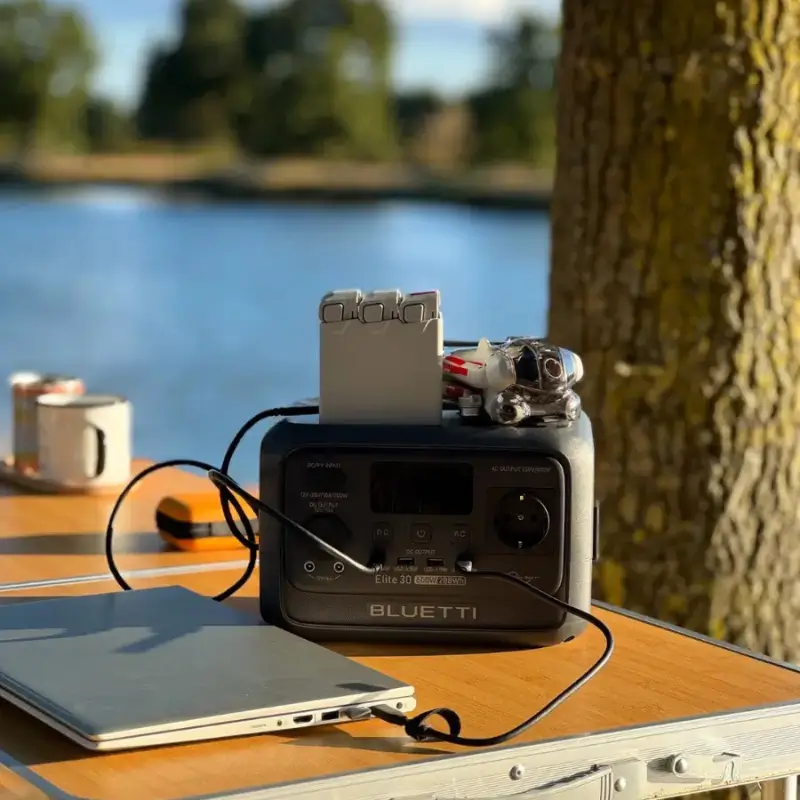 Estação de energia portátil Bluetti Elite 30 V2 em uso ao ar livre carregando um drone e notebook.
